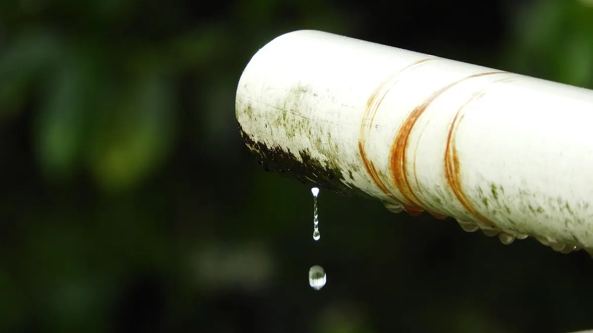 Cano branco enferrujado com gota de água pingando