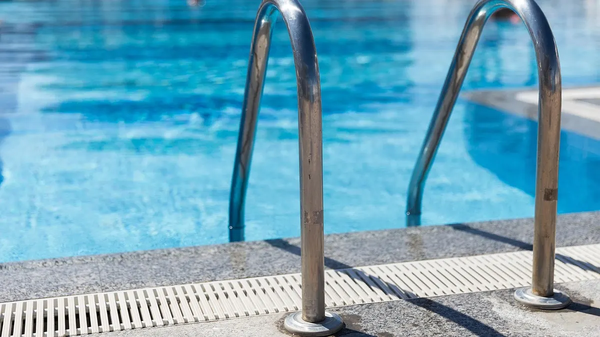 Escada de corrimão metálico dentro de piscina de água azul
