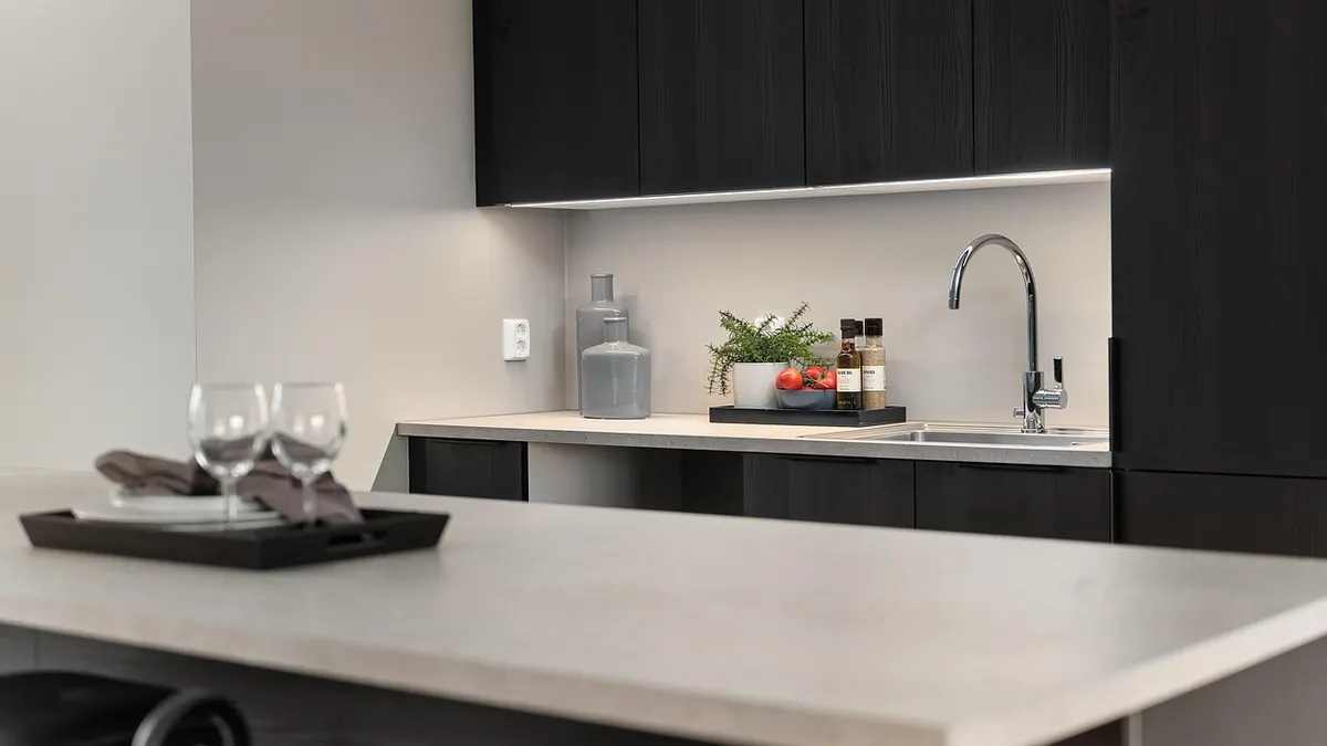 Cozinha moderna com armários escuros, bancada clara e torneira