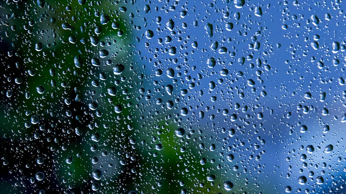 Gotas de água sobre uma superfície de vidro com fundo azul e verde